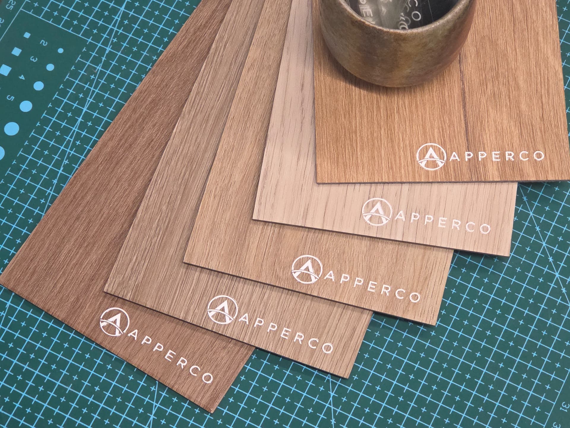 Flat-lay of Apperco-branded wood veneer sample swatches on a cutting mat
